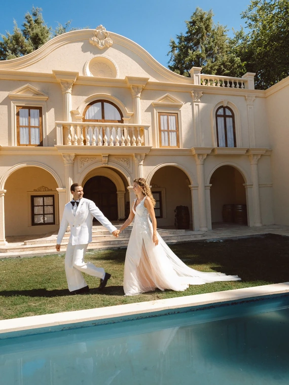 Havuz kenarında el ele yürüyen gelin ve damat