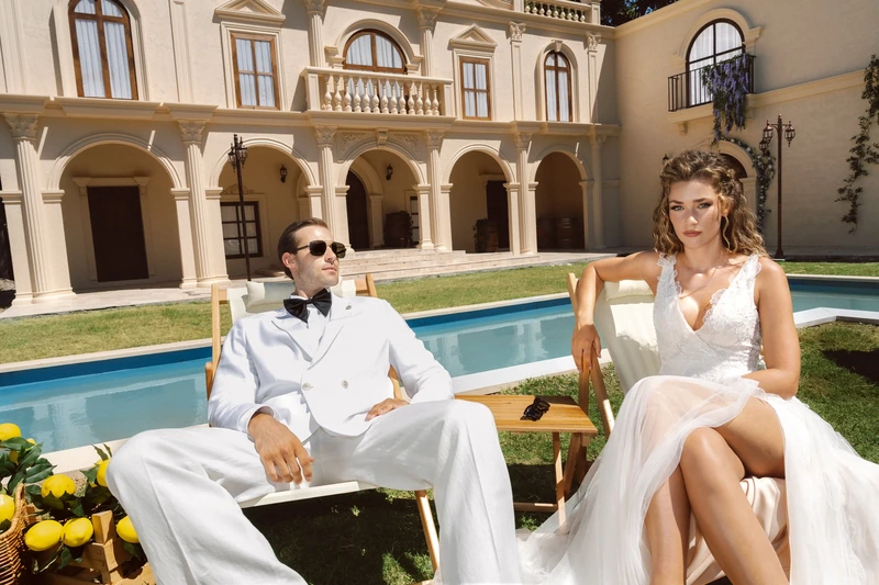Havuz önünde şezlongda oturan güneş gözlüklü damat ve gelin